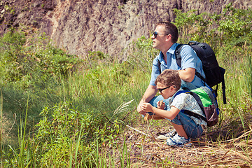 Image showing Father and son siting near the pond at the day time.