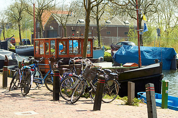 Image showing Bikes and Traditional Dutch Botter Fishing Boats in the small Harbor of the Historic Fishing Village in Netherlands.