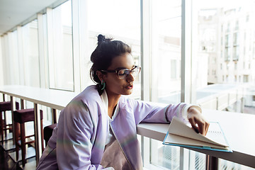 Image showing young cute hipster girl student sitting in cafe with notebook reading, wearing glasses, lifestyle happy smiling people concept