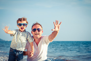 Image showing Father and son playing on the beach at the day time.