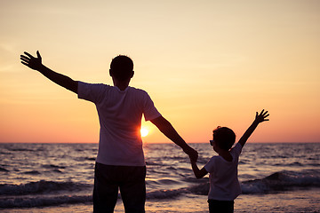 Image showing Father and son playing on the beach at the sunset time.