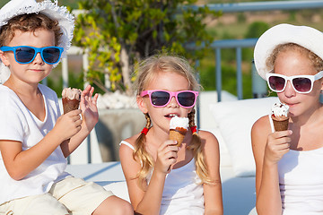 Image showing three happy children eating ice cream near swimming pool at the 
