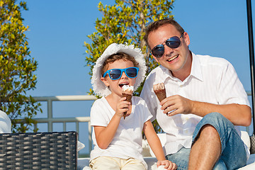 Image showing Father and son relaxing near a swimming pool  at the day time.