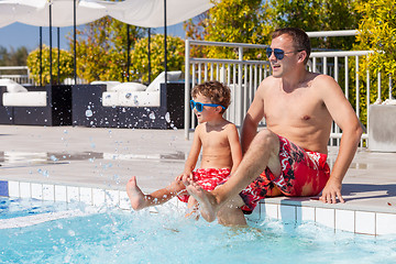 Image showing Father and son relaxing near a swimming pool  at the day time.