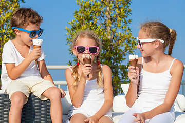 Image showing three happy children eating ice cream near swimming pool at the 