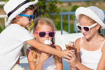 Image showing three happy children eating ice cream near swimming pool at the 