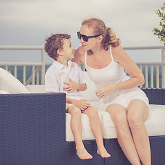 Image showing Mother and son relaxing near a swimming pool  at the day time.