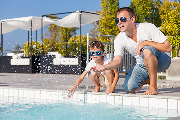 Image showing Father and son relaxing near a swimming pool  at the day time.