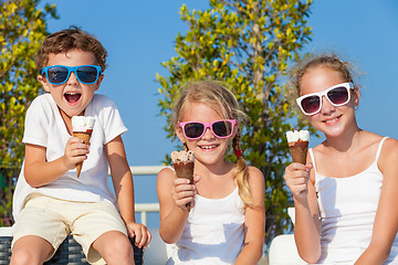 Image showing three happy children eating ice cream near swimming pool at the 