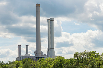 Image showing Industrial smokestack over green forest trees