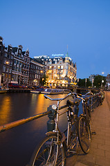 Image showing editorial amsterdam night canal scen with bicycles and boats