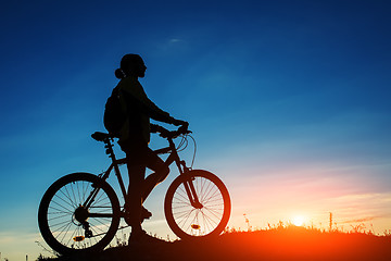 Image showing Silhouette of cyclist and a bike on sky background