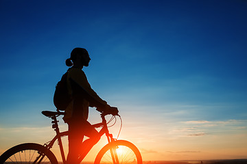 Image showing Silhouette of cyclist and a bike on sky background