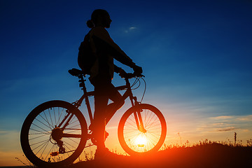 Image showing Silhouette of cyclist and a bike on sky background