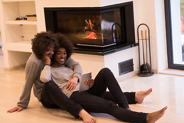 Image showing multiethnic couple using tablet computer on the floor