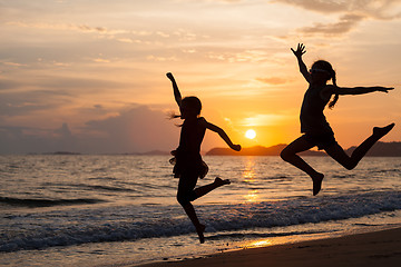 Image showing Two happy girls jumping on the beach 