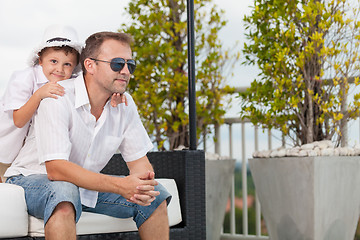 Image showing Father and son relaxing near a swimming pool  at the day time.