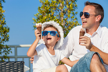 Image showing Father and son relaxing near a swimming pool  at the day time.