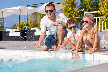 Image showing Father and children playing near a swimming pool  at the day tim