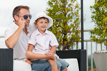 Image showing Father and son relaxing near a swimming pool  at the day time.