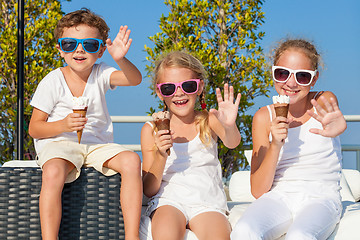 Image showing three happy children eating ice cream near swimming pool at the 