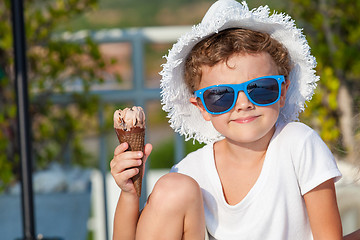 Image showing happy little boy with ice cream  sitting near a swimming pool