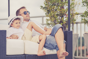 Image showing Father and son relaxing near a swimming pool  at the day time.