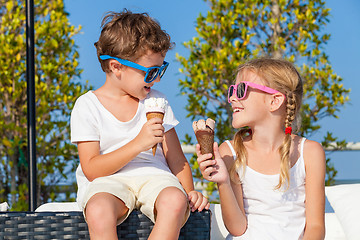 Image showing Two happy children eating ice cream near swimming pool at the da