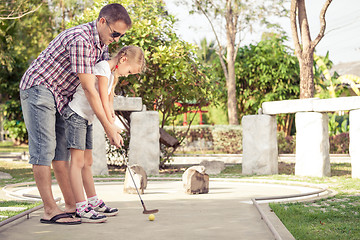 Image showing Cheerful young man teaching his daughter to play mini golf at th