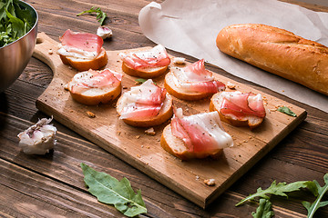 Image showing Wooden cutting board with sandwiches