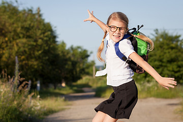 Image showing Smiling young school girl in a school uniform jumping on the roa