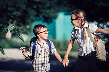 Image showing Smiling young school children in a school uniform jumping on the