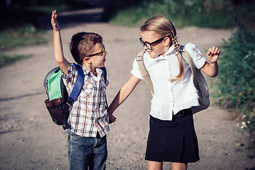 Image showing Smiling young school children in a school uniform jumping on the