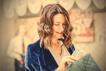 Image showing smiling middle-aged woman with a cheerful face counting cash