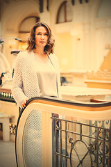 Image showing woman in a light knitted coat near an escalator