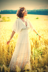 Image showing happy smiling middle-aged woman spinning in a white dress in a f