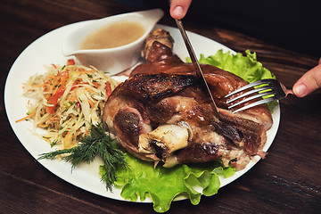 Image showing Man eats tasty dish of pork shank