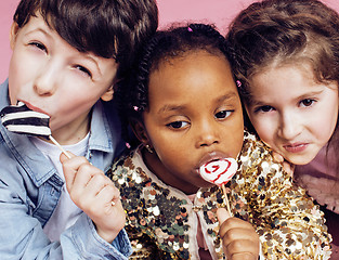 Image showing lifestyle people concept: diverse nation children playing together, caucasian boy with african little girl holding candy happy smiling 