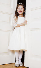 Image showing little cute girl at home, opening door well-dressed in white dress, adorable milk fairy teeth, curious child