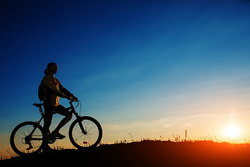 Image showing Silhouette of cyclist and a bike on sky background