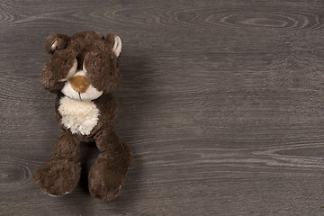 Image showing Sad brown teddy bear on wooden background, top view