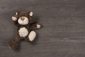 Image showing Brown teddy bear on wooden background, top view