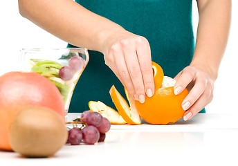 Image showing Cook is peeling orange for fruit dessert