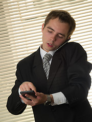 Image showing Businessman with calculator talking phone