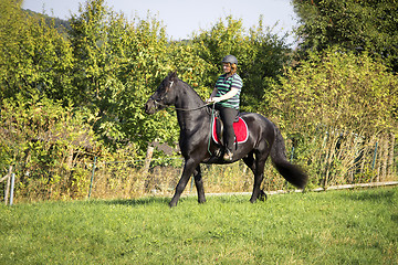 Image showing Beautiful young woman rides her black Horse 