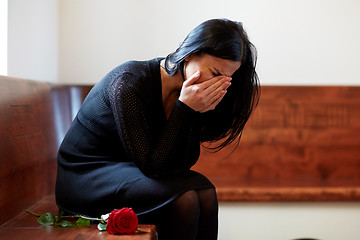 Image showing crying woman with red rose at funeral in church