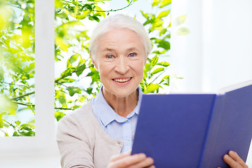 Image showing happy smiling senior woman reading book at home