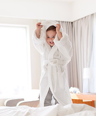 Image showing happy little boy in bathrobe on home or hotel bed