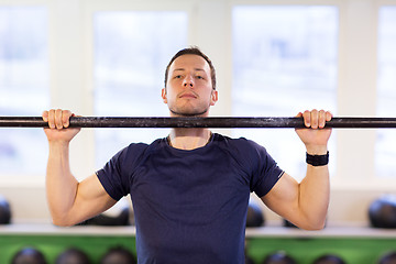 Image showing man exercising on bar and doing pull-ups in gym