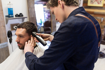 Image showing man and barber with trimmer cutting hair at salon